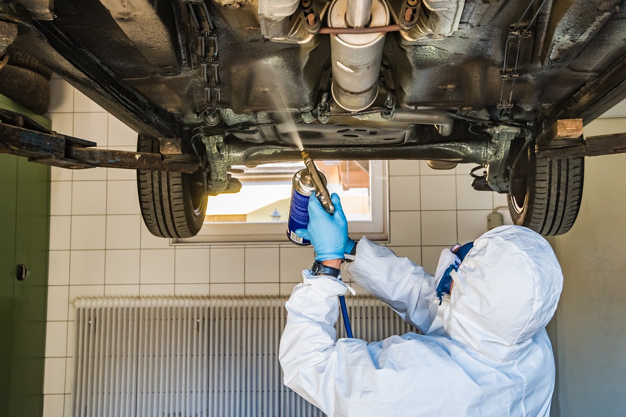 整備士が車の下回りに防錆コーティング剤をスプレーしている様子